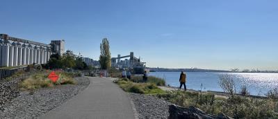 Paved mixed use trail along a waterfront with  grain elevators and shipping terminals alongside