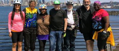 Seven riders in casual clothing including three men and four women of varying ages and ethnicities.