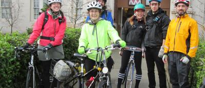 Three women and two men with bike helmets and casual clothing prepare to ride