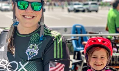 An adult and child park their bikes at Cascade's bike valet during a Sounders game.