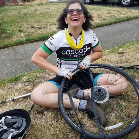 Outrider smiling and changing a tube on the sidewalk